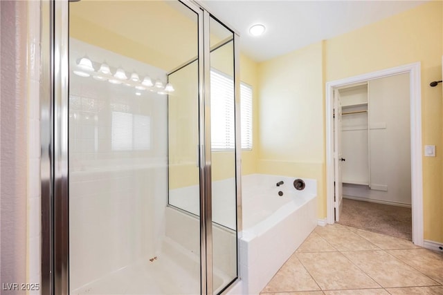 bathroom featuring tile patterned floors, a stall shower, and a bath