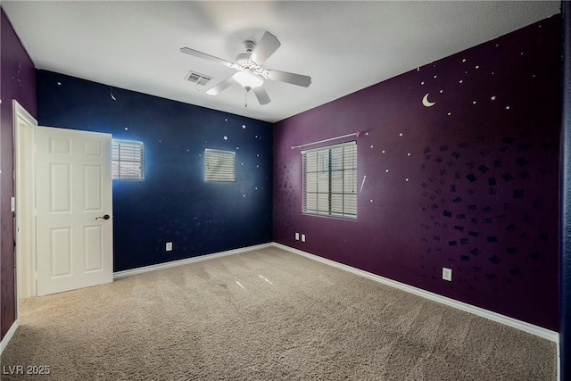 carpeted spare room with visible vents, a ceiling fan, and baseboards