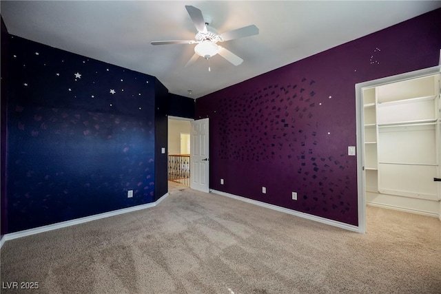 unfurnished bedroom featuring a spacious closet, ceiling fan, baseboards, and carpet