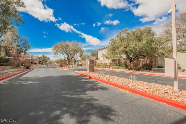 view of road featuring a gate, curbs, and a gated entry