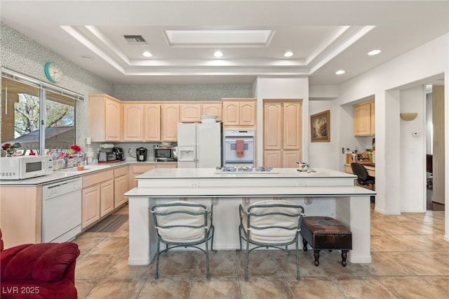 10548 Findlay Ave, Las Vegas, NV 89134 - kitchen with white appliances, light brown cabinetry, a raised ceiling, a center island, and recessed lighting