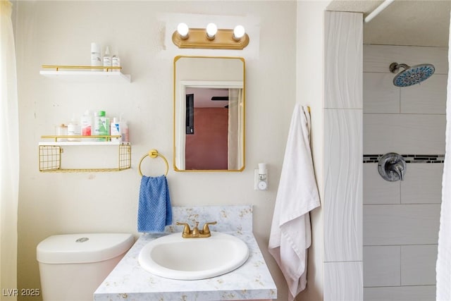 full bath with a tile shower, toilet, and vanity