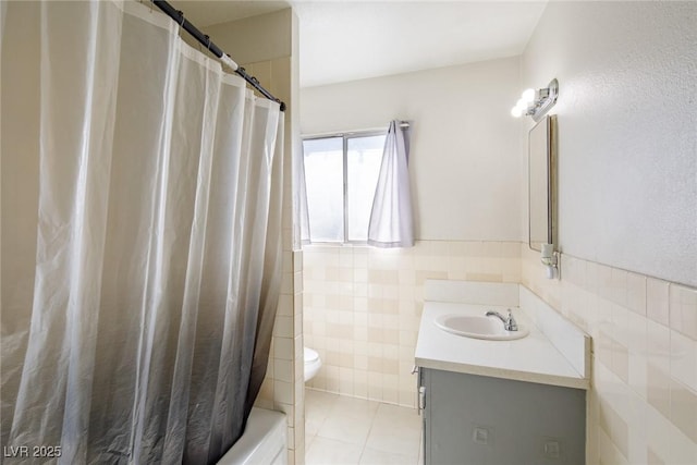 bathroom featuring toilet, tile walls, wainscoting, tile patterned flooring, and vanity