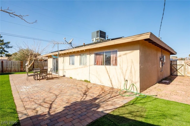 rear view of property with a fenced backyard, stucco siding, a patio, and central AC