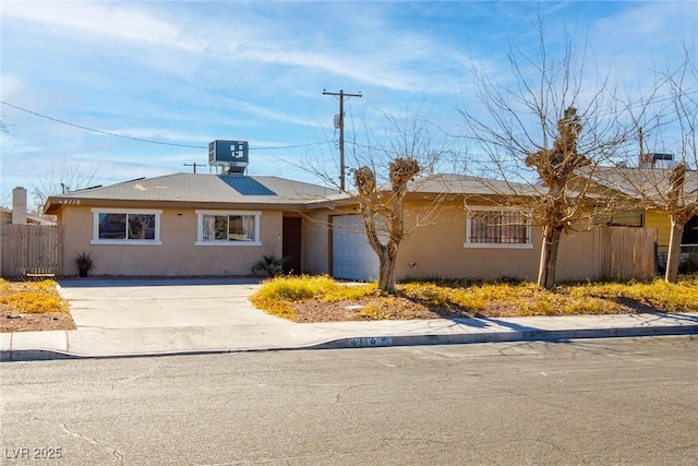 ranch-style house featuring fence, driveway, central AC, stucco siding, and a garage