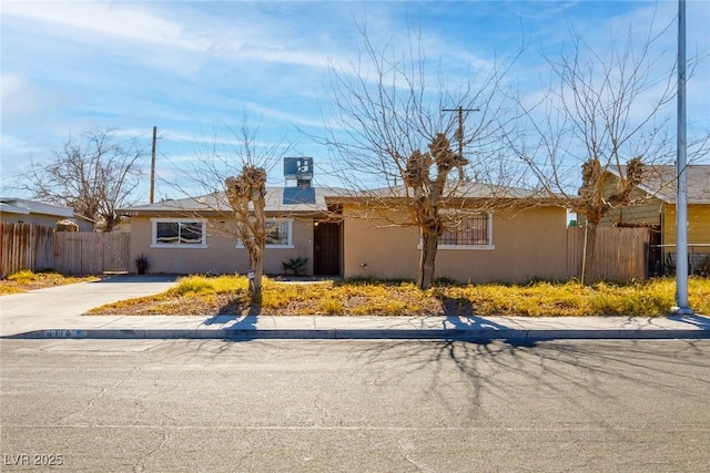 ranch-style home featuring fence, driveway, and stucco siding