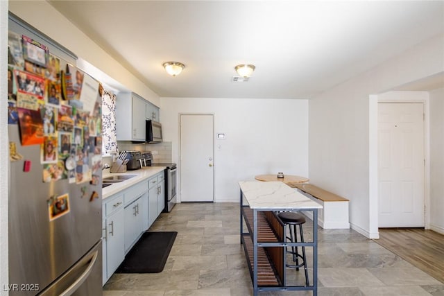 kitchen featuring visible vents, a sink, backsplash, stainless steel appliances, and light countertops