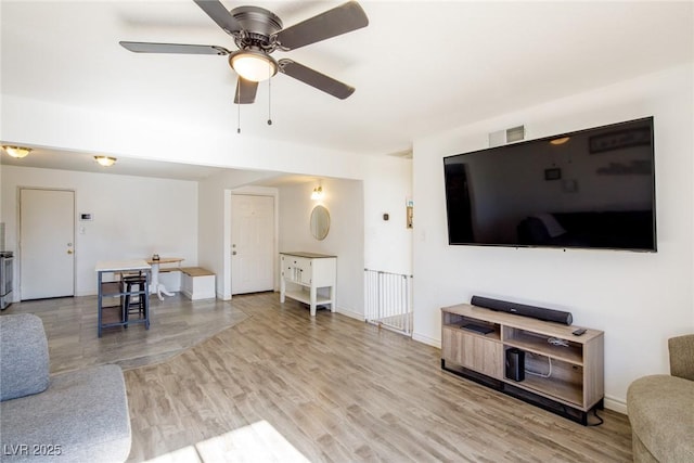 living area featuring visible vents, wood finished floors, baseboards, and ceiling fan