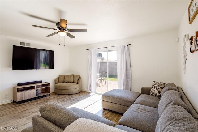 living area with visible vents, baseboards, wood finished floors, and a ceiling fan