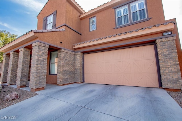 view of front of property with stucco siding, a tiled roof, concrete driveway, and a garage