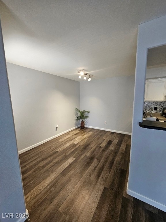 spare room featuring baseboards and dark wood-style flooring