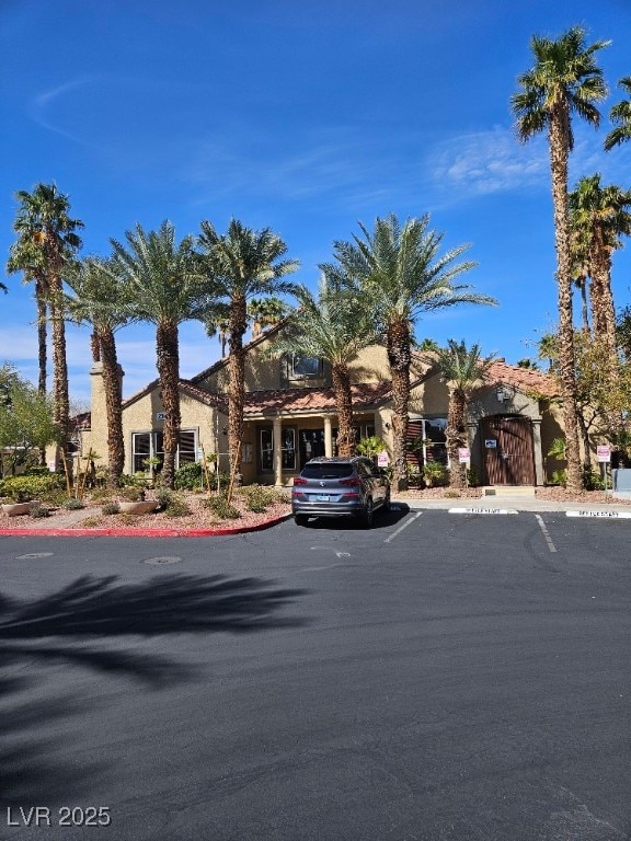 view of front of home featuring stucco siding, uncovered parking, and a gate