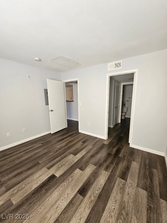 empty room with electric panel, dark wood-style floors, visible vents, and baseboards