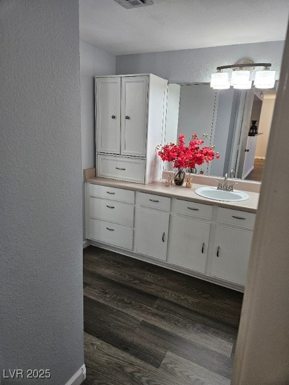 bathroom featuring vanity, wood finished floors, a textured wall, and visible vents