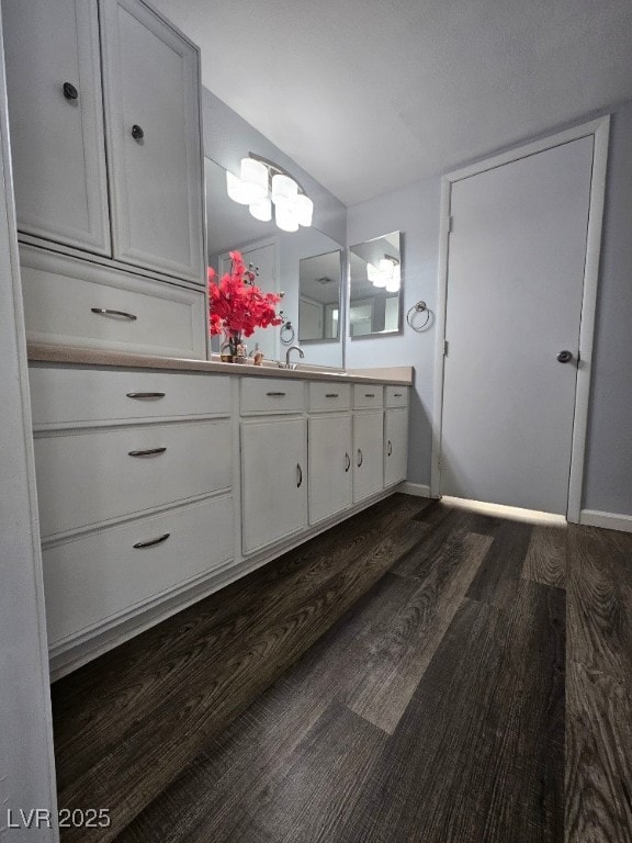 bathroom featuring vaulted ceiling, vanity, baseboards, and wood finished floors