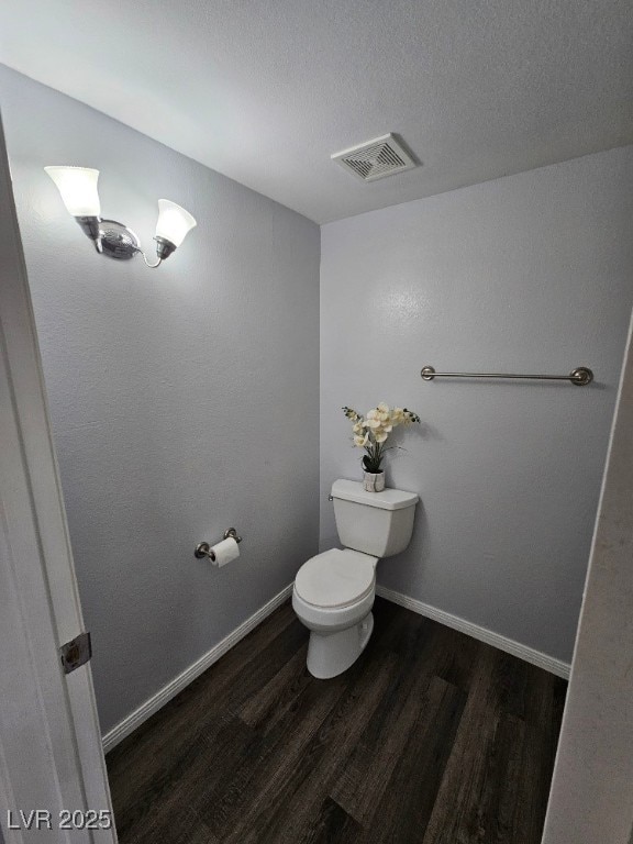 bathroom featuring toilet, wood finished floors, visible vents, and baseboards