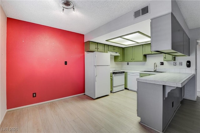 kitchen with visible vents, a sink, white appliances, a peninsula, and green cabinetry