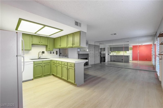 kitchen with a sink, visible vents, white appliances, and green cabinets