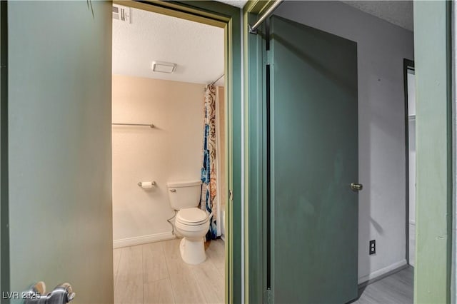 bathroom featuring toilet, a textured ceiling, and wood finished floors