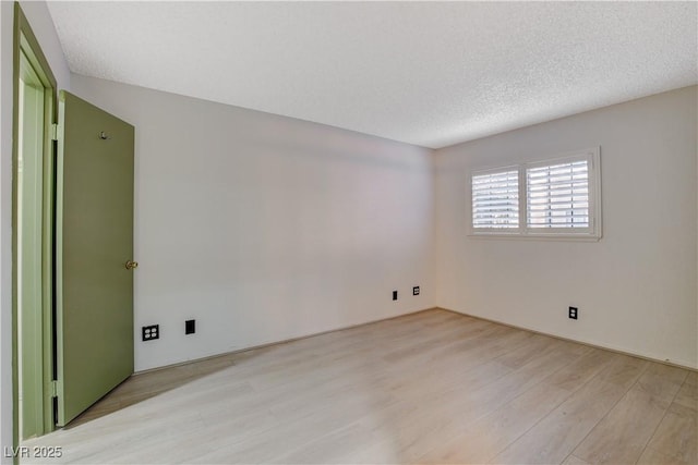 spare room featuring light wood-type flooring and a textured ceiling