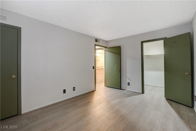 unfurnished bedroom with baseboards, light wood-style floors, visible vents, and a textured ceiling