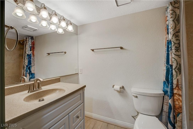 bathroom with baseboards, toilet, vanity, wood finished floors, and a textured ceiling