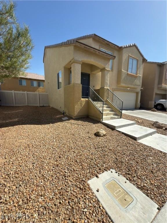 view of front facade featuring stucco siding, an attached garage, concrete driveway, and fence