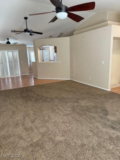 unfurnished living room featuring baseboards, a ceiling fan, carpet, and vaulted ceiling