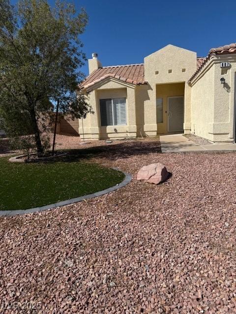 view of front of home featuring stucco siding, a tiled roof, and a chimney