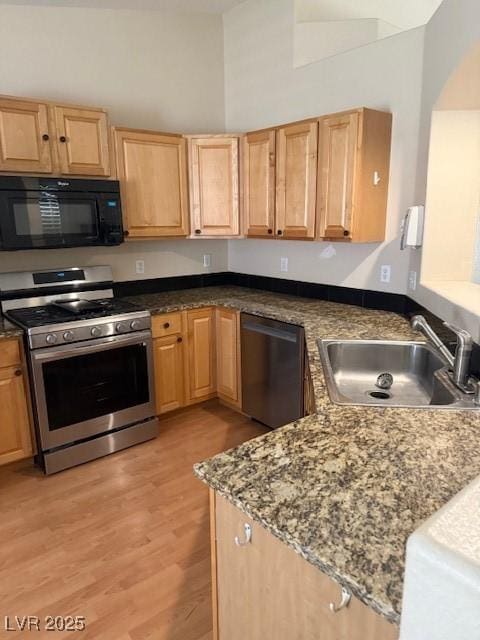 kitchen featuring light brown cabinets, stainless steel appliances, light wood-style floors, and a sink