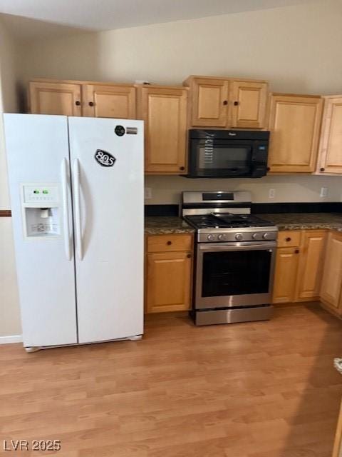 kitchen with light brown cabinetry, dark countertops, white fridge with ice dispenser, black microwave, and stainless steel gas range