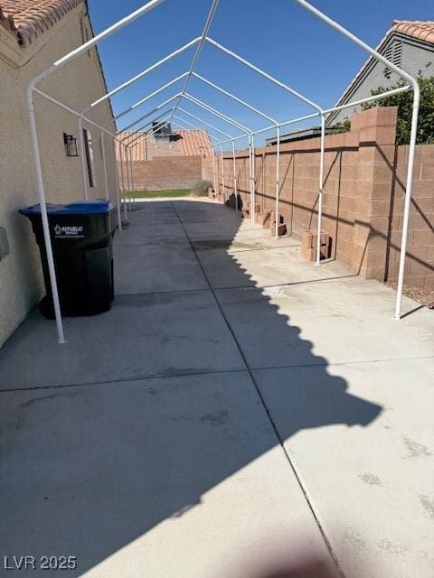 view of patio featuring a lanai, a fenced backyard, and a carport