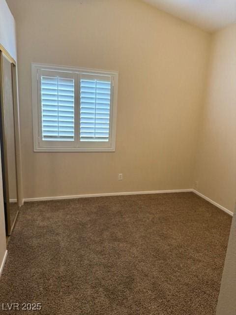 empty room with carpet flooring, lofted ceiling, and baseboards