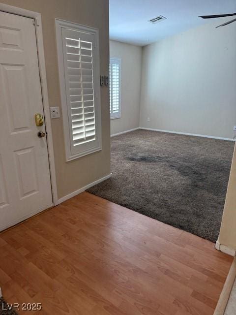 entryway with visible vents, wood finished floors, baseboards, and ceiling fan