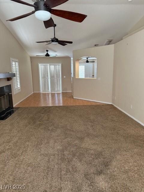 unfurnished living room with a glass covered fireplace, baseboards, carpet, and vaulted ceiling