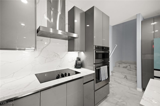 kitchen featuring stainless steel double oven, gray cabinets, black electric stovetop, wall chimney exhaust hood, and modern cabinets