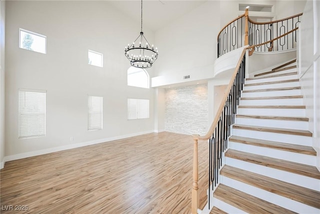 stairway with visible vents, wood finished floors, and a towering ceiling