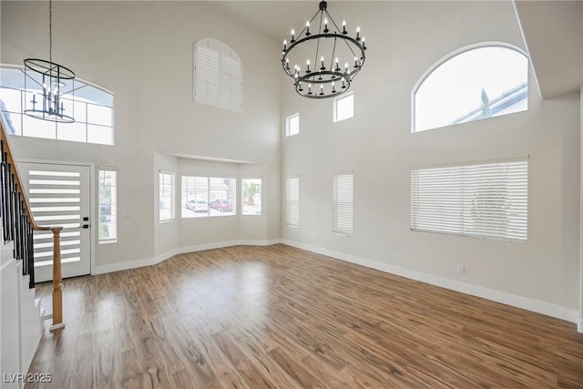 foyer with stairway, baseboards, an inviting chandelier, and wood finished floors