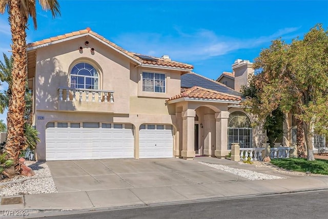 mediterranean / spanish-style home featuring stucco siding, concrete driveway, a garage, solar panels, and a tiled roof