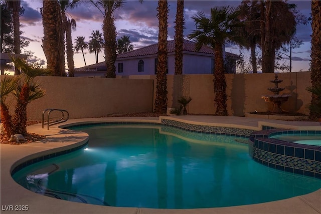 view of swimming pool featuring a fenced backyard and a pool with connected hot tub