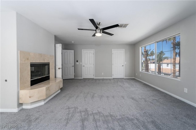 unfurnished living room featuring visible vents, a ceiling fan, a high end fireplace, carpet floors, and baseboards