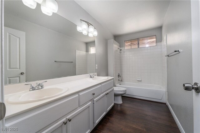 bathroom featuring a sink, toilet, wood finished floors, and bathtub / shower combination