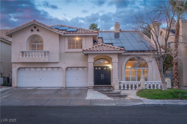 mediterranean / spanish-style house featuring a tile roof, concrete driveway, stucco siding, a chimney, and an attached garage