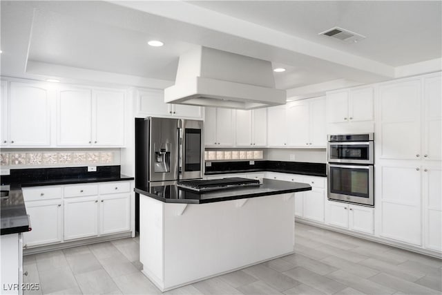 kitchen featuring dark countertops, visible vents, range hood, appliances with stainless steel finishes, and white cabinets