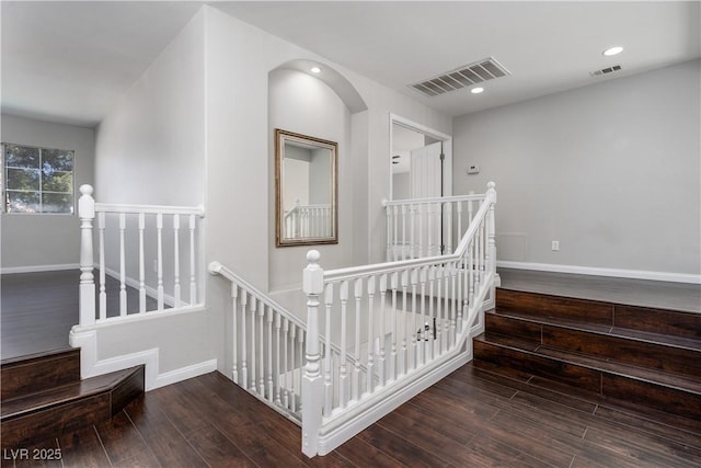 interior space with visible vents, an upstairs landing, baseboards, and wood finished floors