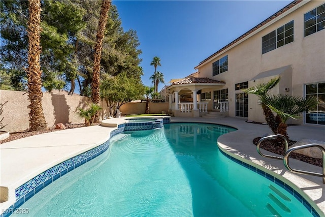 view of swimming pool featuring a patio, a fenced backyard, and a pool with connected hot tub