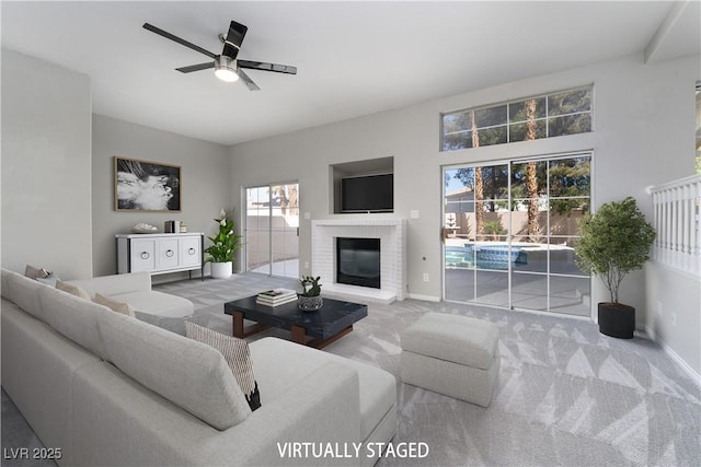 carpeted living area featuring a fireplace, a ceiling fan, and baseboards