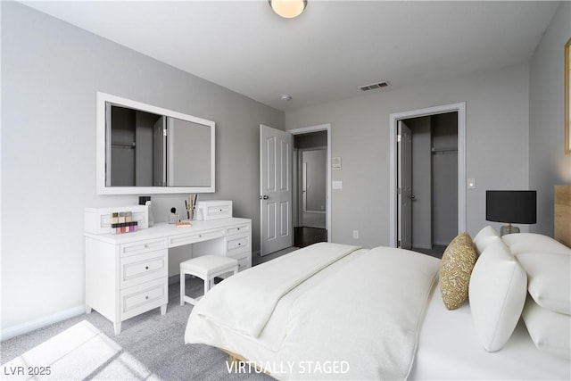 bedroom featuring light carpet, visible vents, a walk in closet, and baseboards