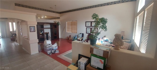 living room featuring arched walkways, tile patterned floors, and a wealth of natural light