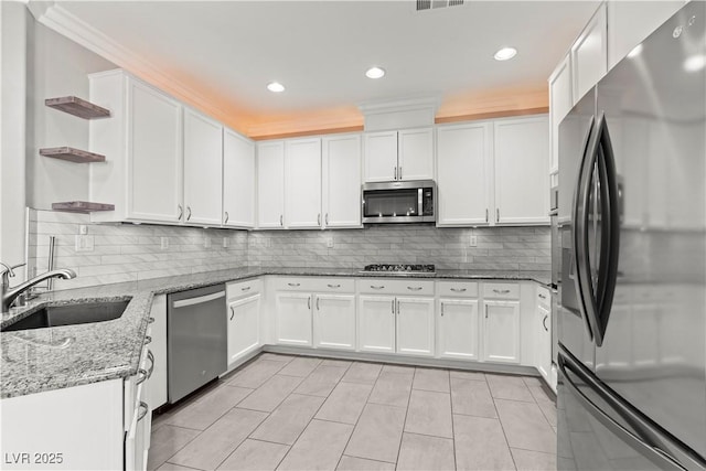 kitchen featuring a sink, backsplash, white cabinets, stainless steel appliances, and open shelves